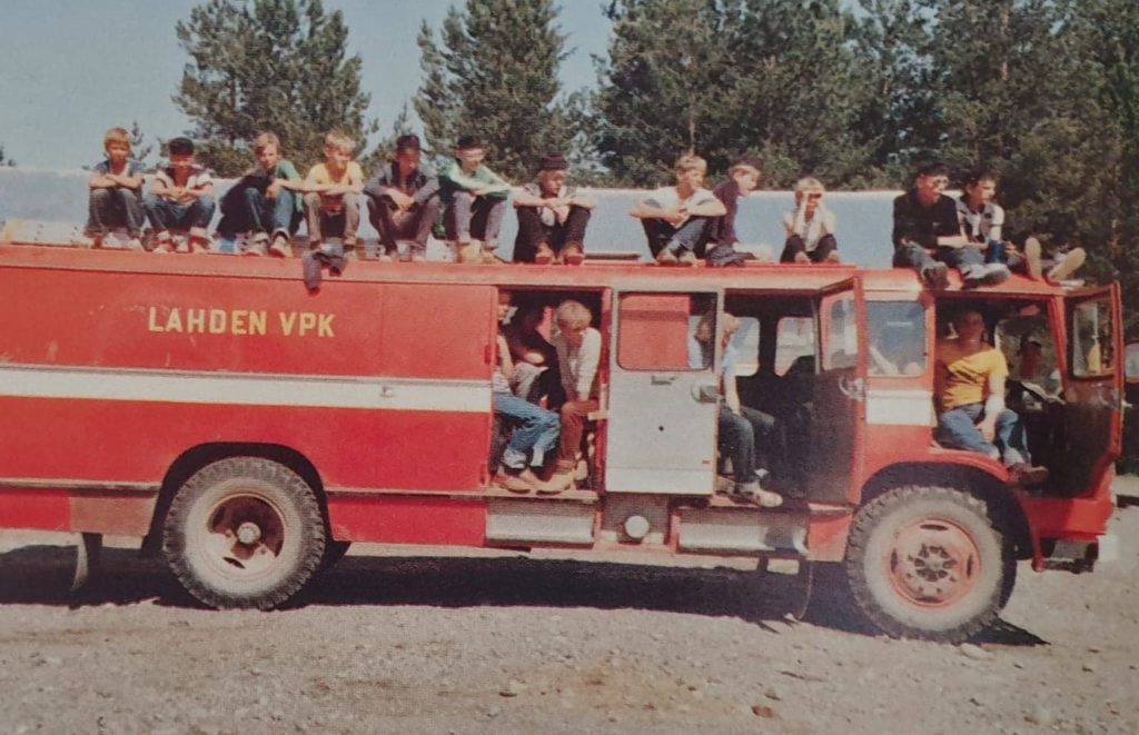 Vanhassa kuvassa iso joukko nuoria paloauton katolla ja sisällä. Kyljessä lukee Lahden VPK.